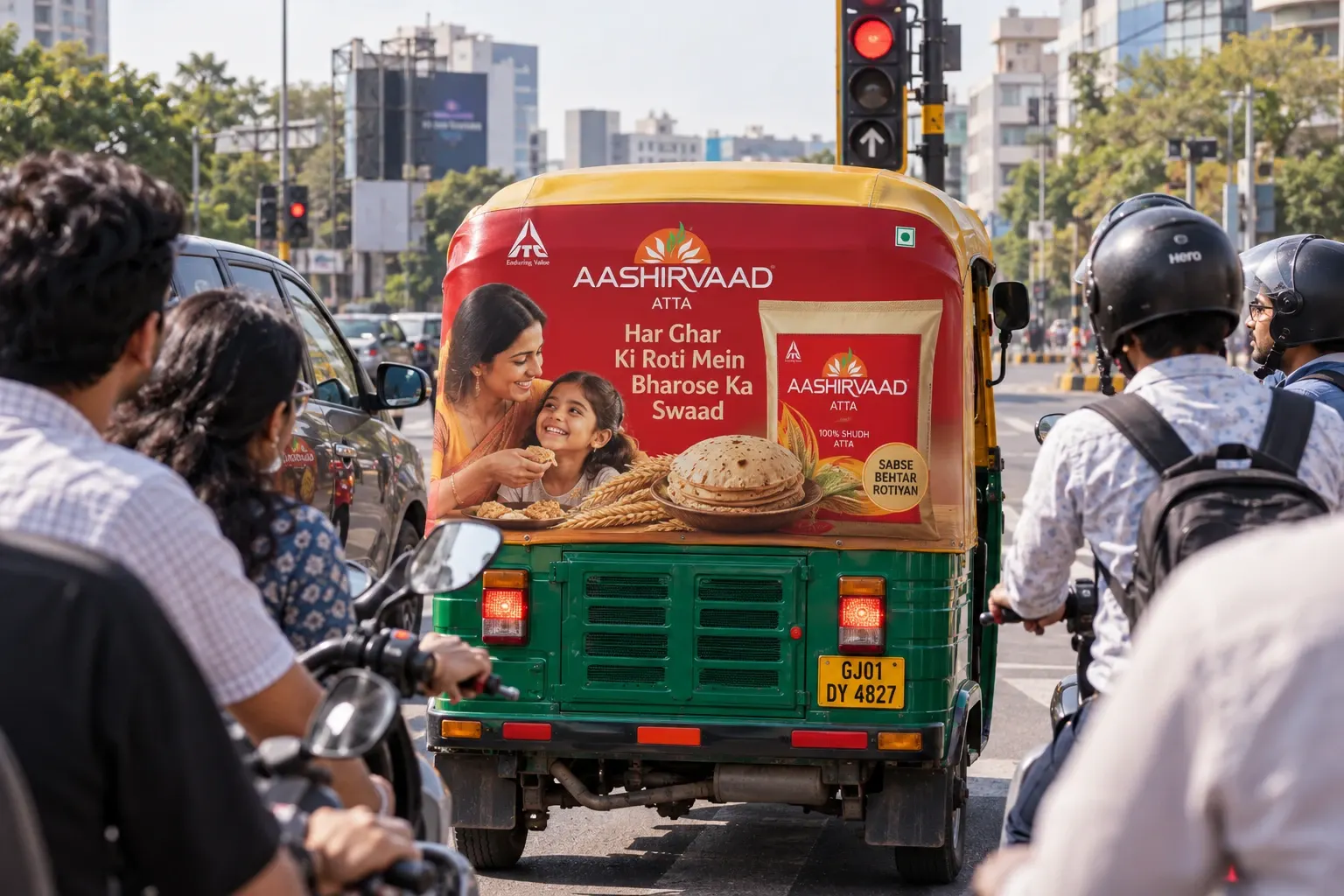 An auto-rickshaw with a full rear-hood advertisement waiting at a traffic light in the city